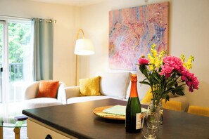 Ein Zimmer mit Esstisch, einer Weinflasche und einem Blumenstrauß.