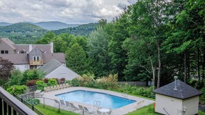 A backyard with a swimming pool, a small deck, and a fenced area. - 1BR, 2nd Floor Condo at Sugarbush (Warren)
