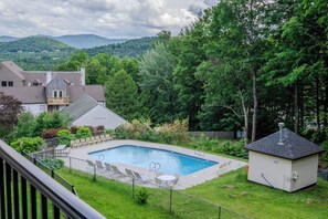 Ein Garten mit Pool, einer kleinen Holzterrasse und einem umzäunten Bereich.