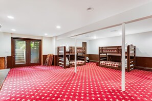 Een kamer met stapelbedden, een tapijt met een rood sterrenpatroon en een deur die naar buiten leidt.