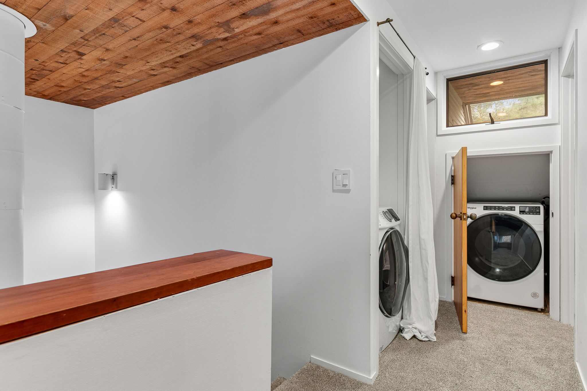A laundry room with a washing machine, dryer, and wooden ceiling.