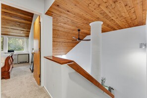 Un interior moderno con techo de madera, pared blanca y escalera de madera.
