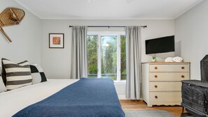 A bedroom with a bed, a dresser, a television, and a fireplace. - The Warren Nook: Your cozy, modern mountain basecamp. (Warren)
