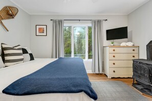 Um quarto com uma cama, penteadeira, televisão e lareira.