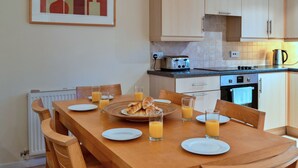 Eine Küche mit Holzausstattung, einem Esstisch mit Tellern, Gläsern und Croissants.