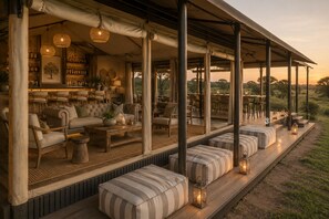 An outdoor lounge area with sofas, a bar, and a view of the landscape.