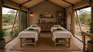 Una habitación con carpa, dos camas, un aparador de madera, una estantería con botellas y vistas al exterior.