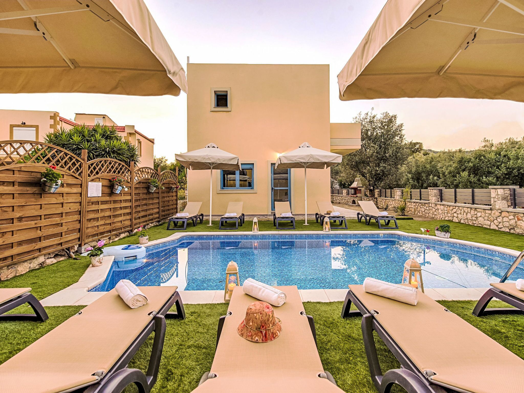 A pool area with lounge chairs, umbrellas, and a small building with a window.