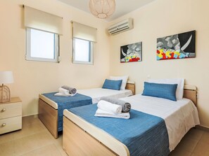 Habitación de hotel con dos camas, una mesita de noche, una lámpara y obras de arte en las paredes.