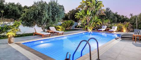 A swimming pool with lounge chairs and a pergola.