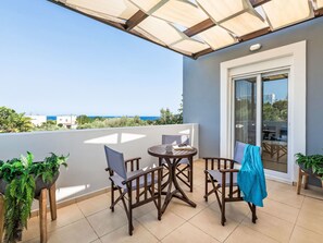 A balcony with a table and chairs, a glass door, and a view of the sea. - Vacation home Olvia by Interhome (Gennadi)