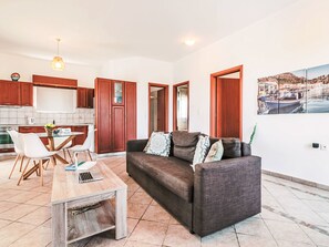 A living room with a sofa, coffee table, and dining area with chairs. - Deep Blue by Interhome (Lachania)