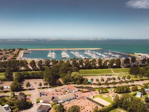 Luftaufnahme eines Yachthafens mit zahlreichen vor Anker liegenden Booten, umgeben von Grünflächen und Wohngebieten.