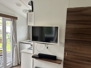 Eine moderne Küche mit Flachbildfernseher, Backofen und Holzschrank.