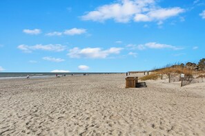 A wide sandy beach with footprints, a wooden structure, and a clear sky. - 
Coastal Retreat Steps from Coligny Beach, Dining, Shops, and Celebration Park! (Hilton Head Island)