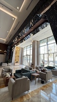 Eine großzügige Lobby mit Sitzbereichen, großen Fenstern und einem modernen Design.