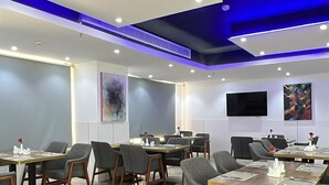A modern conference room with tables, chairs, and a flat-screen TV on the wall. - Medhal Hotel (Jeddah)