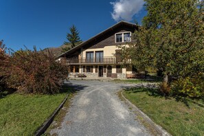 Ein zweigeschossiges Haus mit Balkon, Kiesweg und umliegender Bepflanzung.