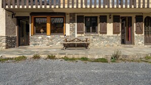 A stone building with a wooden balcony, stone steps, and a bench.