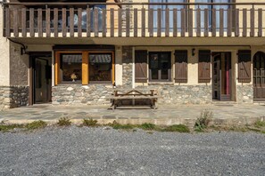 A stone building with a wooden balcony, stone steps, and a bench.