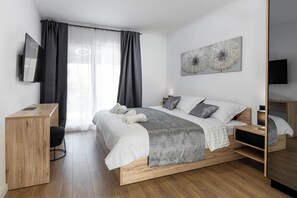 Een moderne slaapkamer met een houten bed, een bureau, een stoel en een televisie.