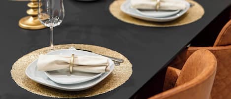 A dining table set with gold placemats, white plates, and gold candelabras.