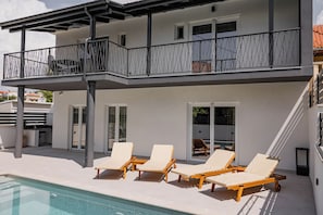 Ein modernes, zweistöckiges Gebäude mit Balkon, Außenbereich und Schwimmbad.