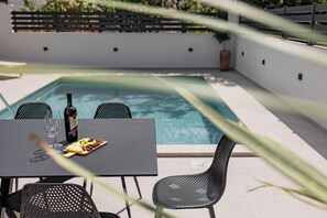 A poolside setting with a table, chairs, a bottle of wine, and a plate of food. - Villa Luce
Wonderful 3-bedroom house with heated pool in charming Podstrana (Podstrana)