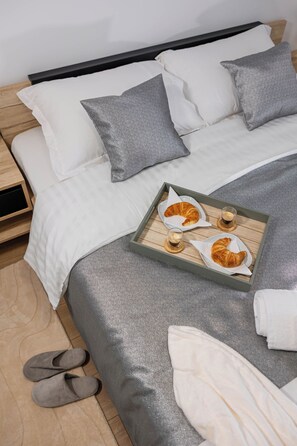 A neatly made bed with white linens and grey pillows, a tray with croissants and coffee, and grey slippers on the floor. - Villa Luce
Wonderful 3-bedroom house with heated pool in charming Podstrana (Podstrana)