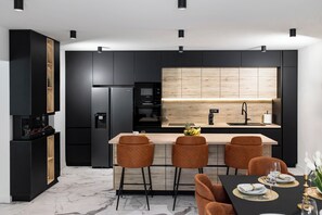 Een moderne keuken met een centraal eiland, zwarte kastjes en een houten achterwand.