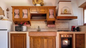 Una cocina con gabinetes de madera, un microondas, una estufa a gas y un horno empotrado.