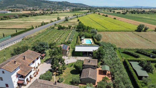 Propiedad rural con piscina, paneles solares y una carretera al fondo.