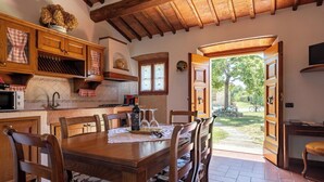 Una cocina rústica con armarios de madera, una mesa de comedor y vistas al jardín.