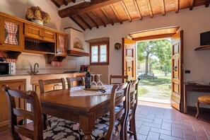 Eine rustikale Küche mit Holzschränken, einem Esstisch und Blick auf den Garten.