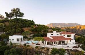 A modern two-story house with a swimming pool, surrounded by lush greenery and hills. - Los Tilos Estate: Luxury Spanish Estate with Iconic LA Views & Private Pool (Los Angeles)