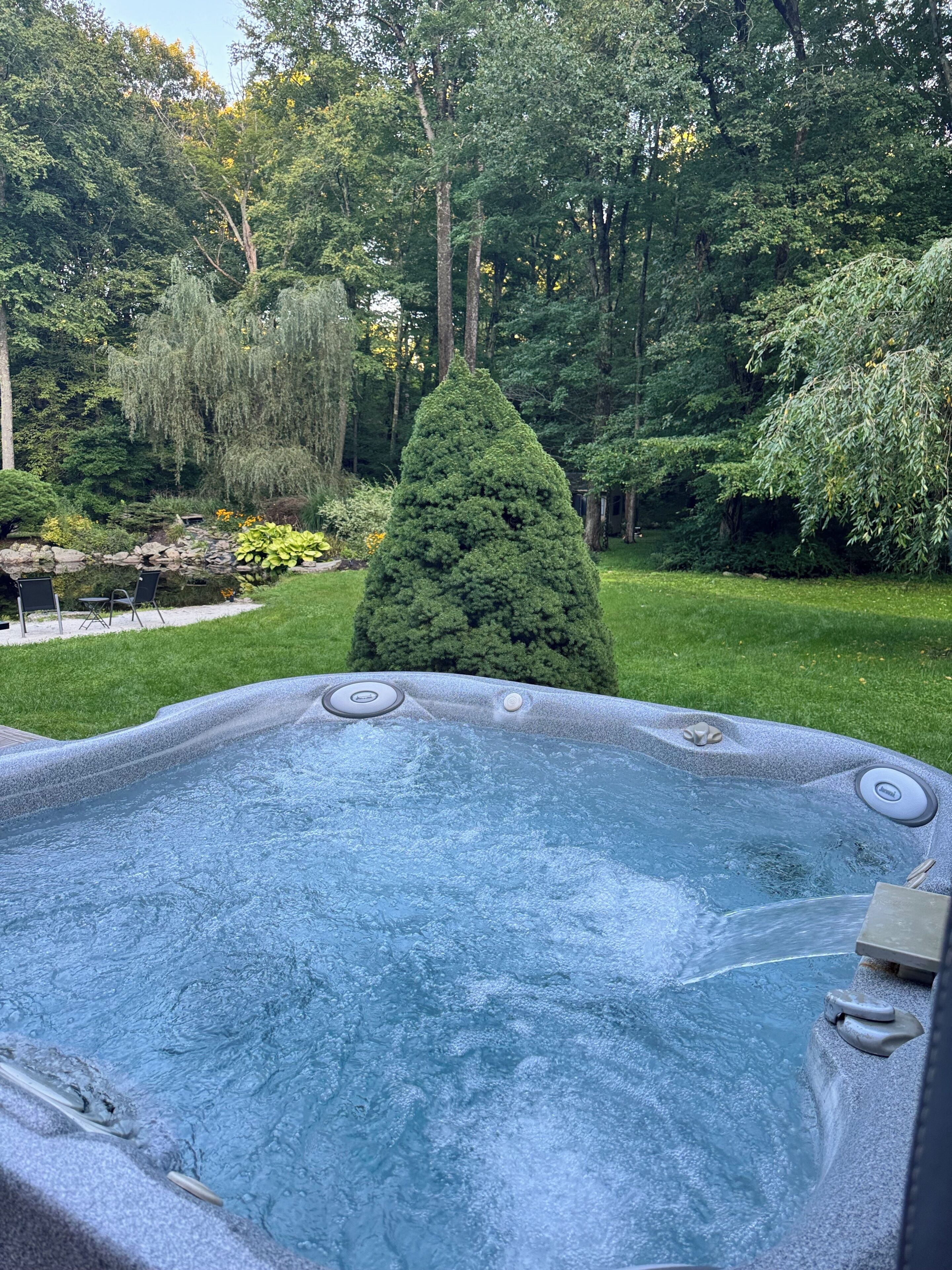 Un bain à remous entouré d’un jardin où poussent différentes plantes et arbres.