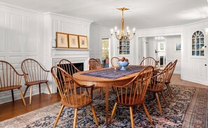 A dining room with a round table, wooden chairs, a chandelier, and a fireplace. - The 1775 Colonel Benjamin Tallmadge House on the Litchfield Green (Litchfield)