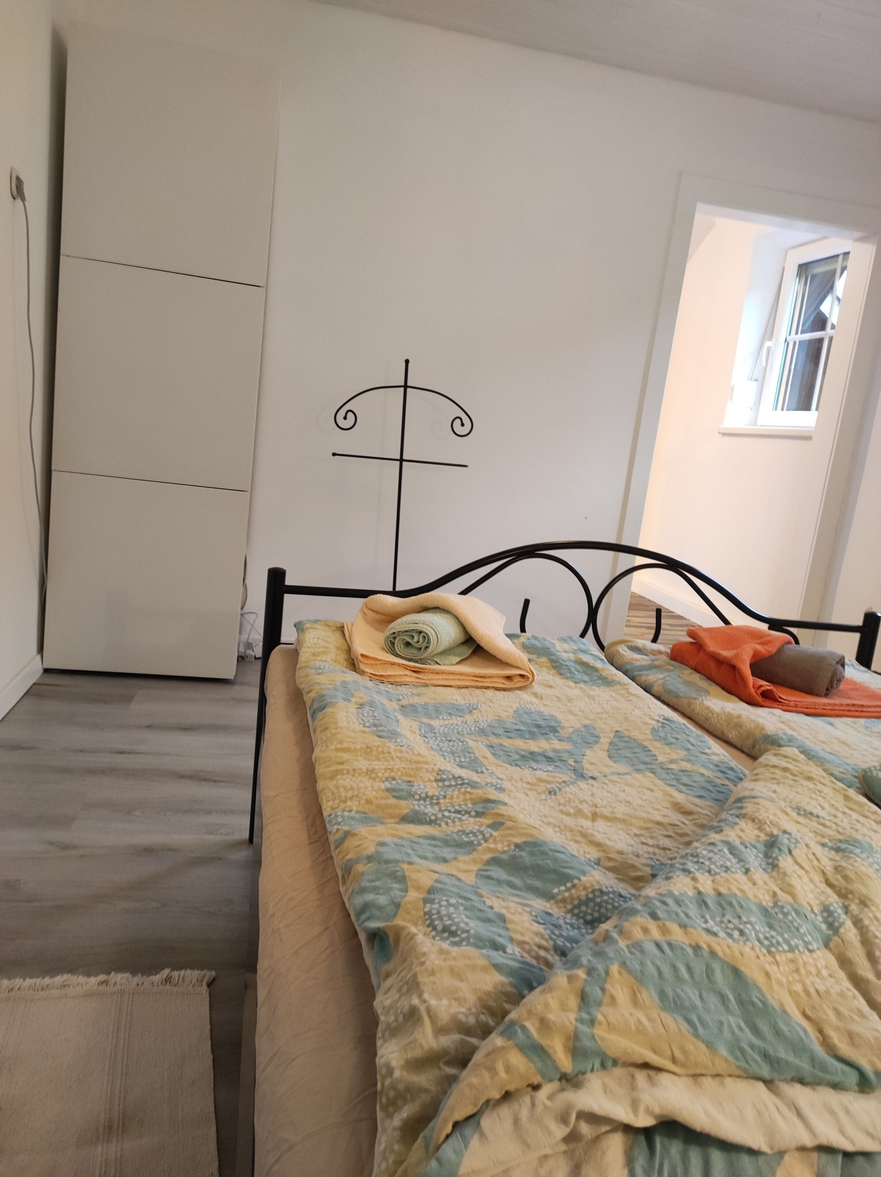 A bedroom with a bed, a wardrobe, a window, and a door.