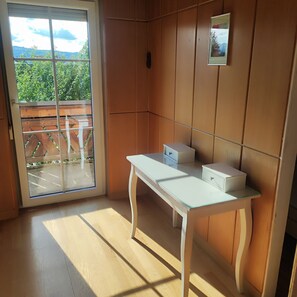 A room with a sliding glass door leading to a balcony, a white table with drawers, and a framed picture on the wall. - Charming vacation home near the lake (Weyregg am Attersee)