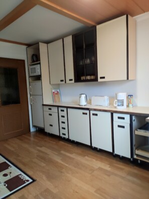 A kitchen with white cabinets, a microwave, a refrigerator, and a coffee maker. - Charming vacation home near the lake (Weyregg am Attersee)