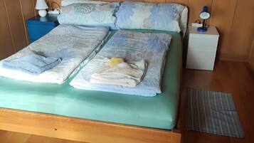 A bed with a green mattress, multiple pillows, and a blue nightstand with a lamp.