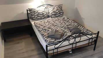 A single bed with a patterned bedspread, a bedside table, and a wall-mounted light fixture.