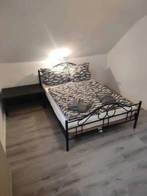 Un lit simple avec une couvre-lit à motifs, une table de chevet et un luminaire fixé au mur.