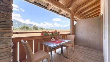 A wooden deck with a table and chairs, overlooking a mountainous landscape.