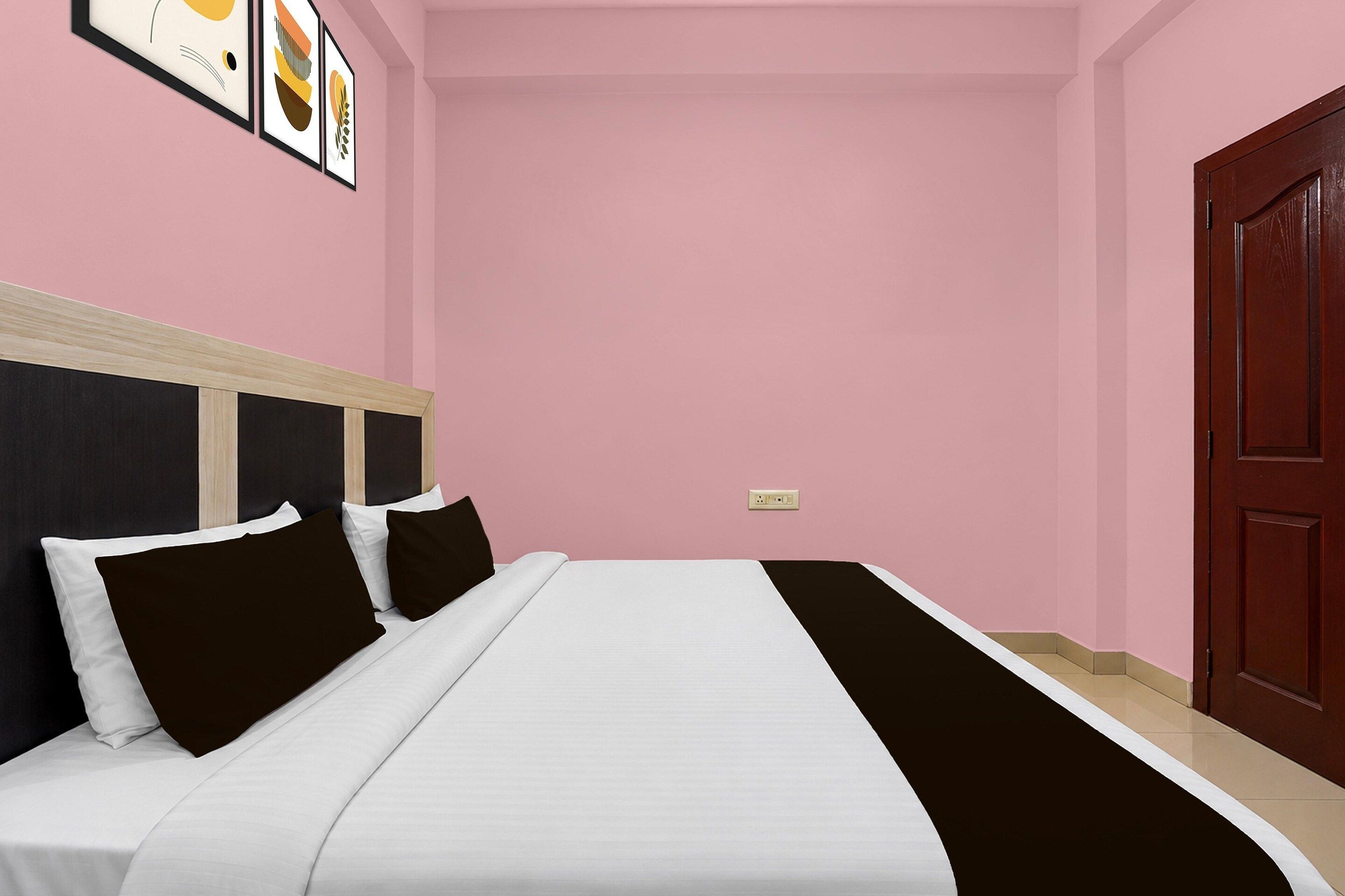 Un dormitorio con cama, cabecera, una puerta y un interruptor de luz instalado en la pared.