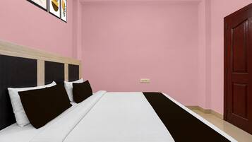 Un dormitorio con cama, cabecera, una puerta y un interruptor de luz instalado en la pared.