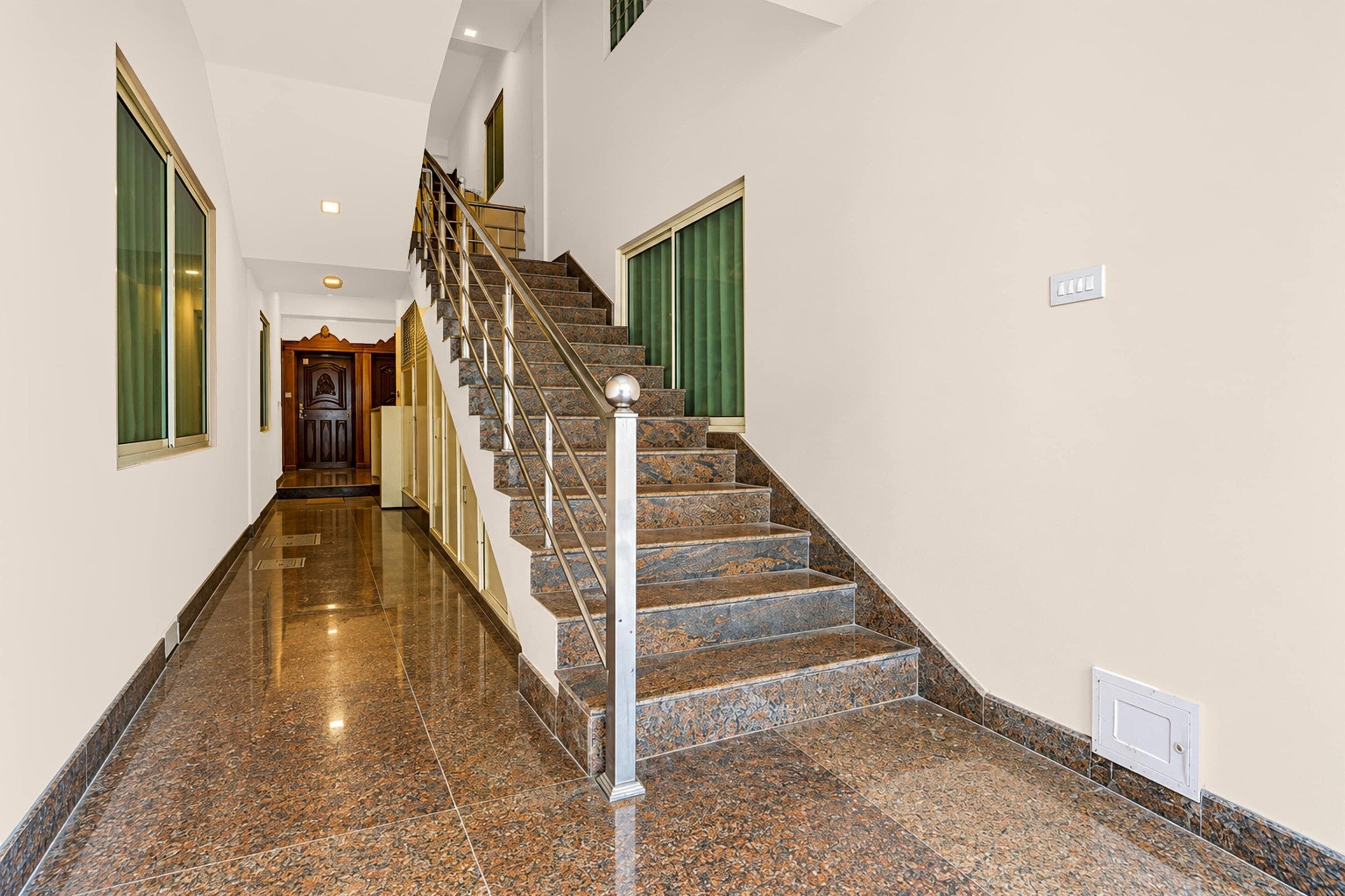 A polished marble staircase with a handrail, leading to a landing with a door.