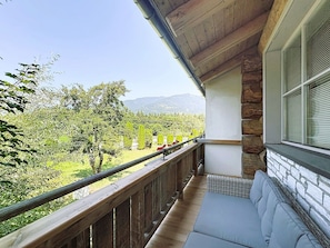 Ein Balkon mit Blick auf einen angelegten Garten und ferne Berge.