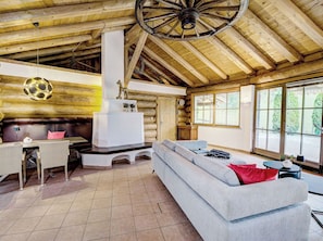 Ein rustikales Holzhaus-Interieur mit Kamin, einer Couch, einem Essbereich und großen Fenstern.