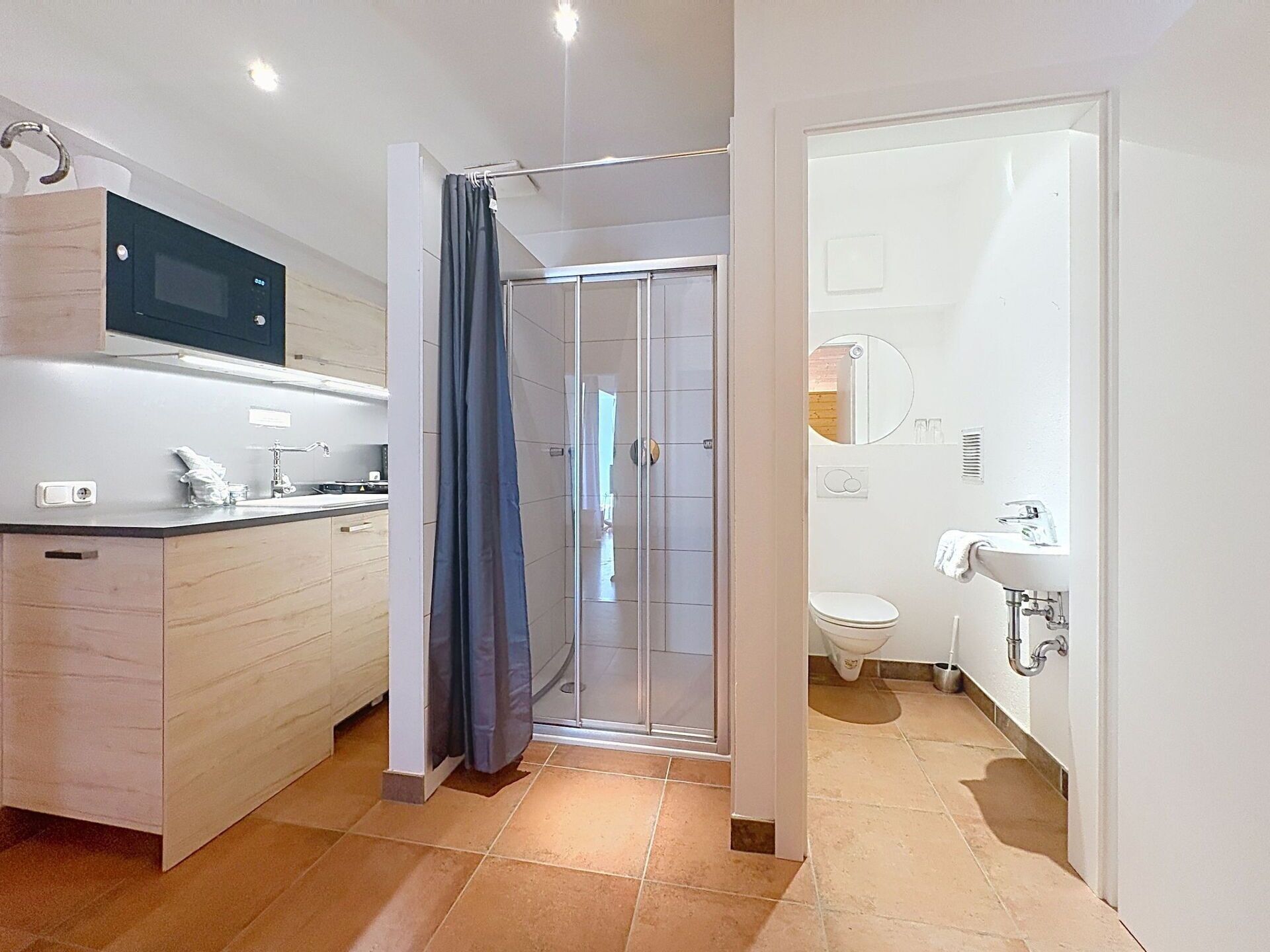 Een moderne badkamer met douche, toilet en wastafel.